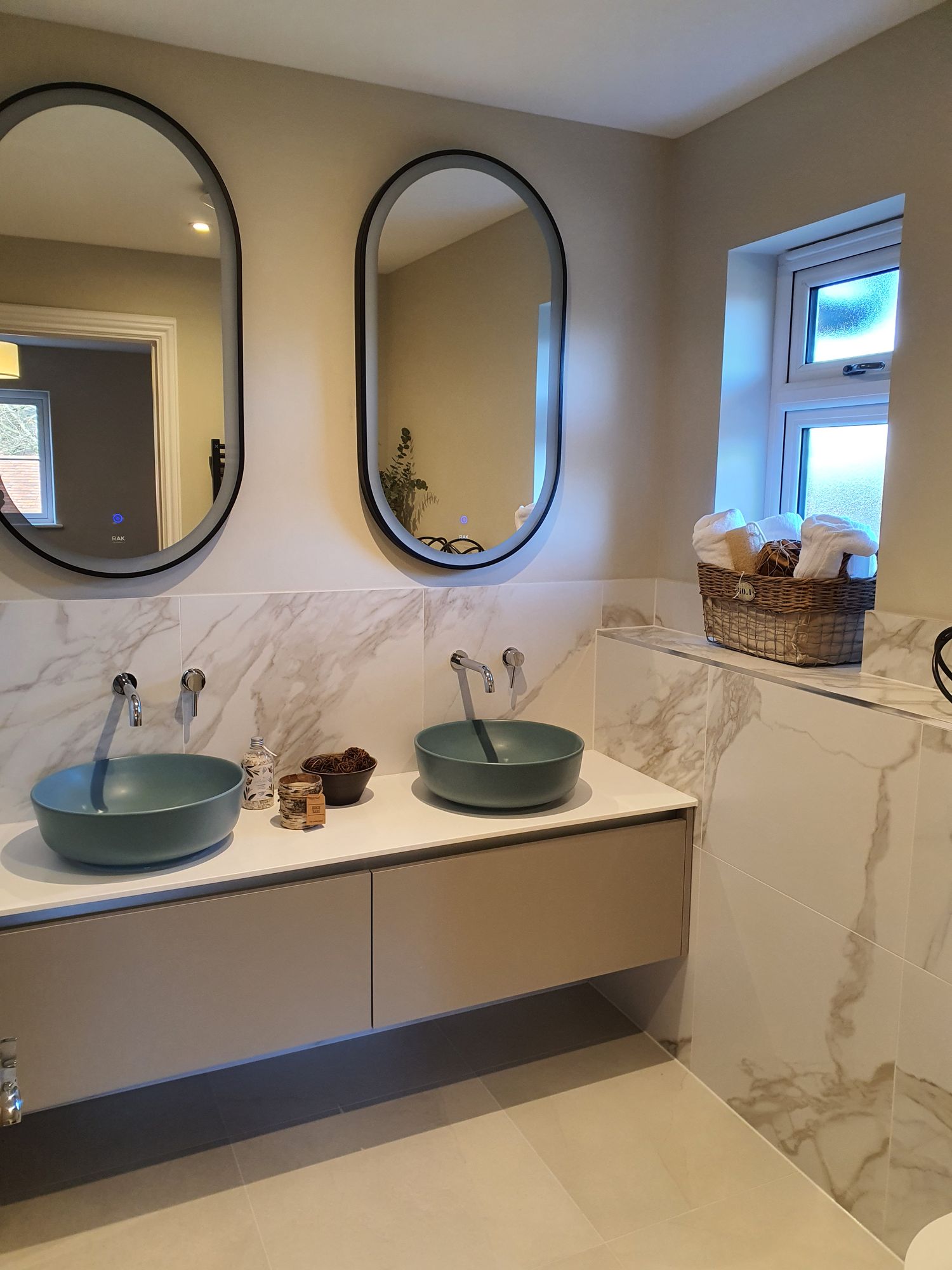 Bathroom with twin illuminated mirrors and green countertop basins