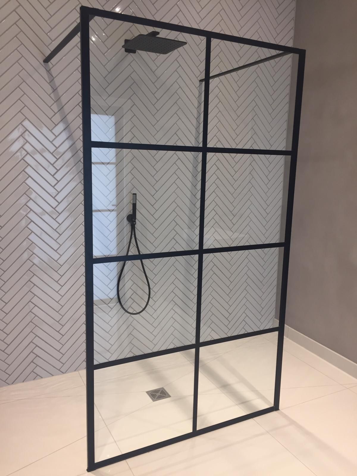 Black-framed walk-in shower screen on herringbone tiling